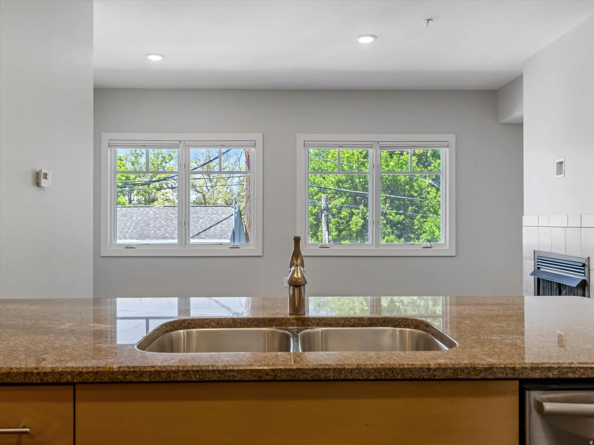 Kitchen island featuring a double basin stainless steel sink with a high-arch faucet, set into a polished stone countertop