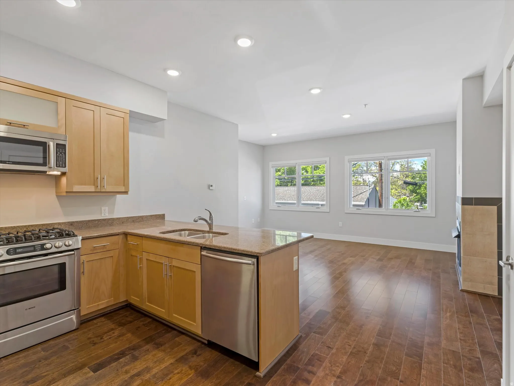 Open-concept kitchen and living area featuring wood-finish flooring, recessed lighting, and light-toned cabinetry