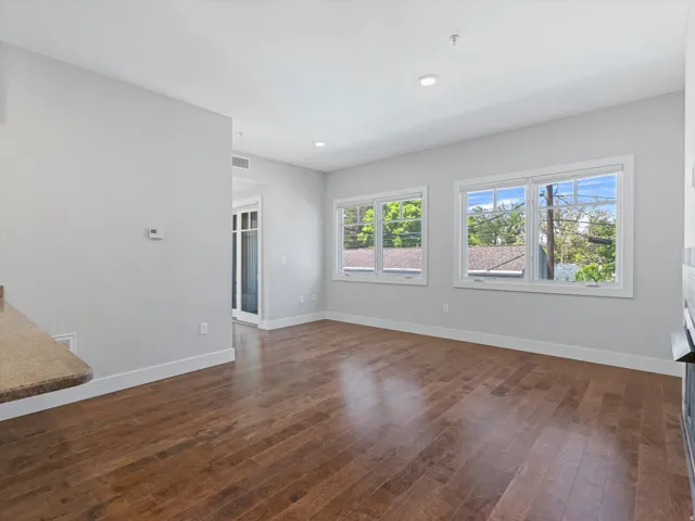 Spacious room featuring wood-finish flooring, light grey wall paint, and multiple windows with white trim