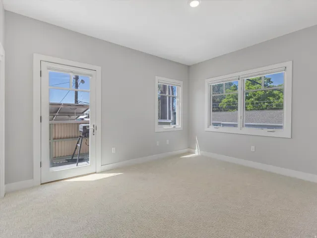 Carpeted room featuring multiple windows and a glass-paneled door