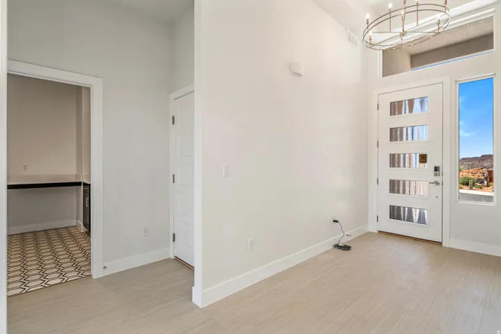 Foyer showcasing a modern front door with frosted glass panels, an adjacent sidelight, high ceilings, and light wood-finish flooring