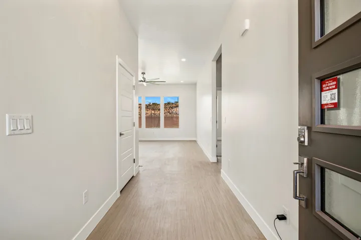 Entryway featuring light wood-finish flooring, white walls, and a modern dark-paneled front door with frosted glass inserts