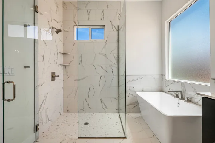Walk-in shower with clear glass enclosure and contrasting floor tile