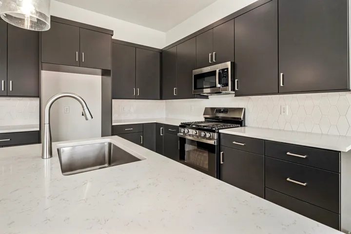 Kitchen featuring dark cabinetry, stainless steel appliances, a stainless steel sink, a gooseneck faucet, and white countertops