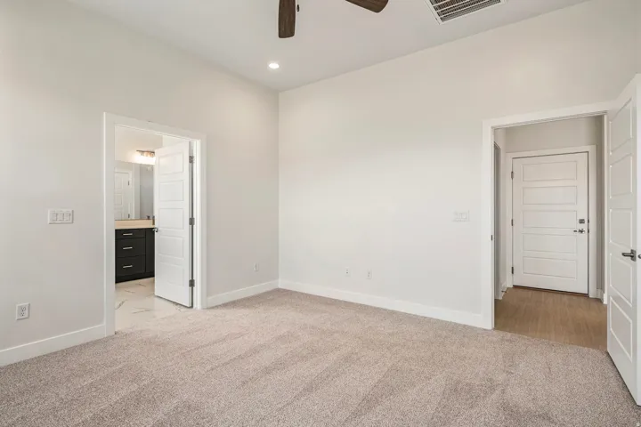 Spacious room featuring neutral carpet flooring, recessed lighting, and a ceiling fan