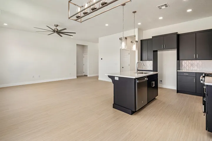 Open concept kitchen with dark cabinetry, white countertops, stainless steel appliances, and a tiled backsplash