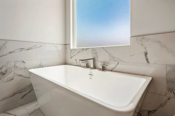 Freestanding soaking tub featuring a deck-mounted faucet and hand shower