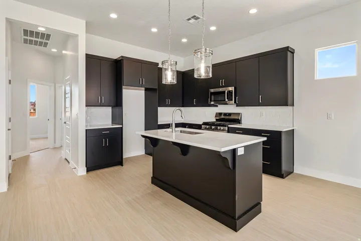 Kitchen featuring dark cabinetry, light countertops, subway tile backsplash, and stainless steel appliances