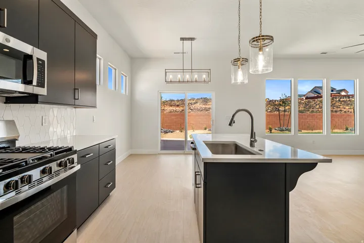 Modern kitchen featuring dark cabinetry, stainless steel appliances, and a white hexagonal tile backsplash