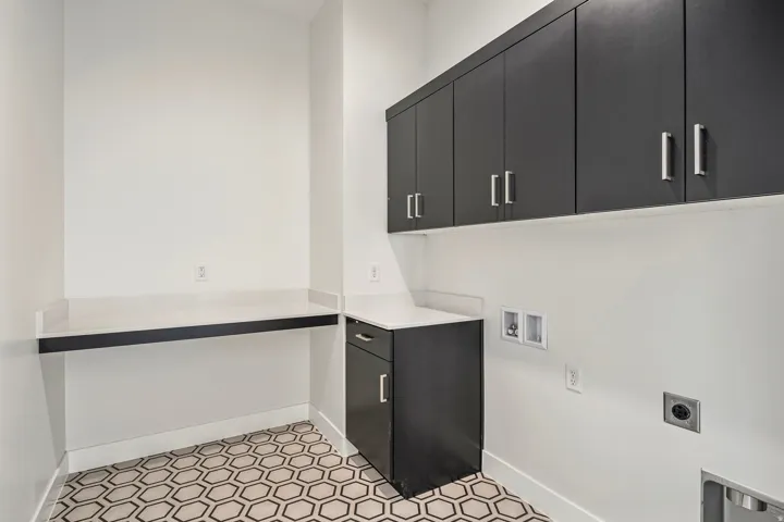Laundry room featuring hexagon tile flooring, white walls, and dark cabinetry with brushed nickel hardware