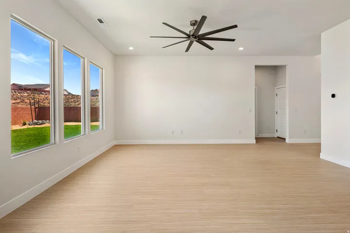 Expansive room featuring multiple vertical windows overlooking a landscaped yard and distant terrain