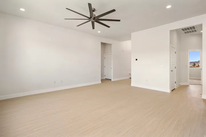 Spacious room featuring light wood-finish flooring and a contemporary ceiling fan with multiple blades