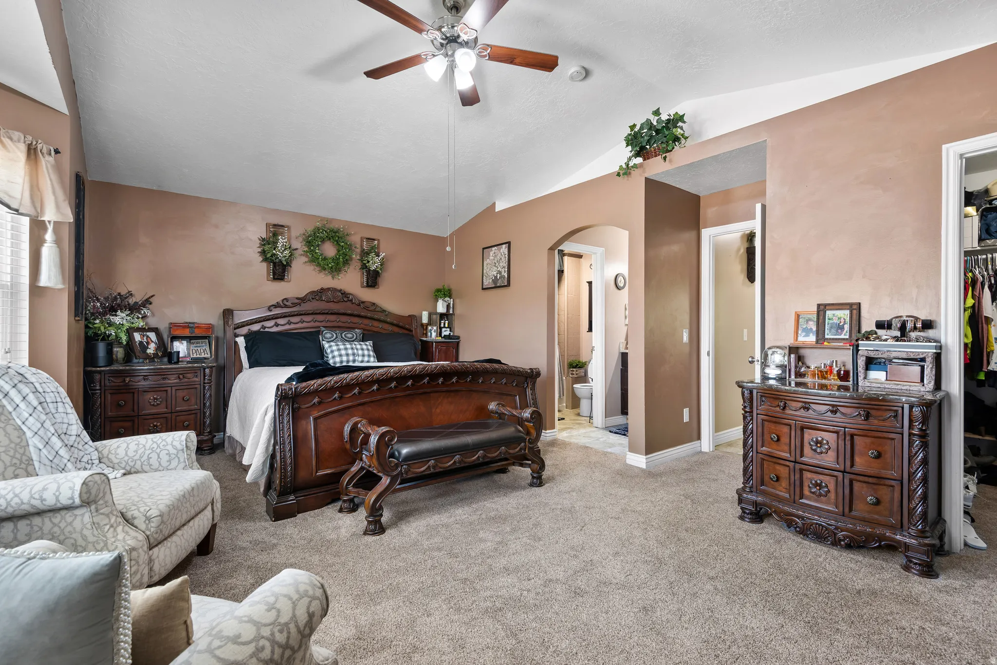 Spacious bedroom featuring vaulted ceilings, carpet flooring, a ceiling fan, and access to an adjoining bathroom