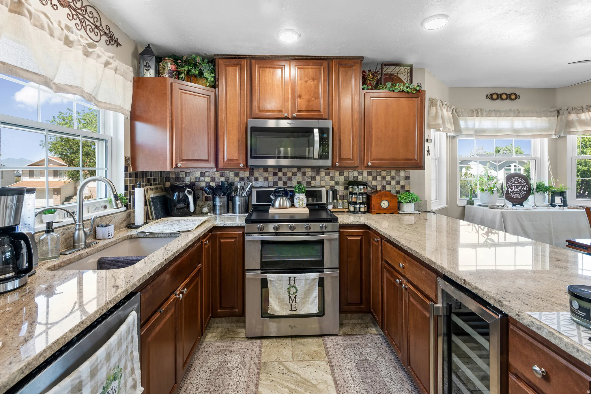 U-shaped kitchen featuring wood cabinetry, granite countertops, stainless steel appliances, mosaic tile backsplash, and recessed lighting