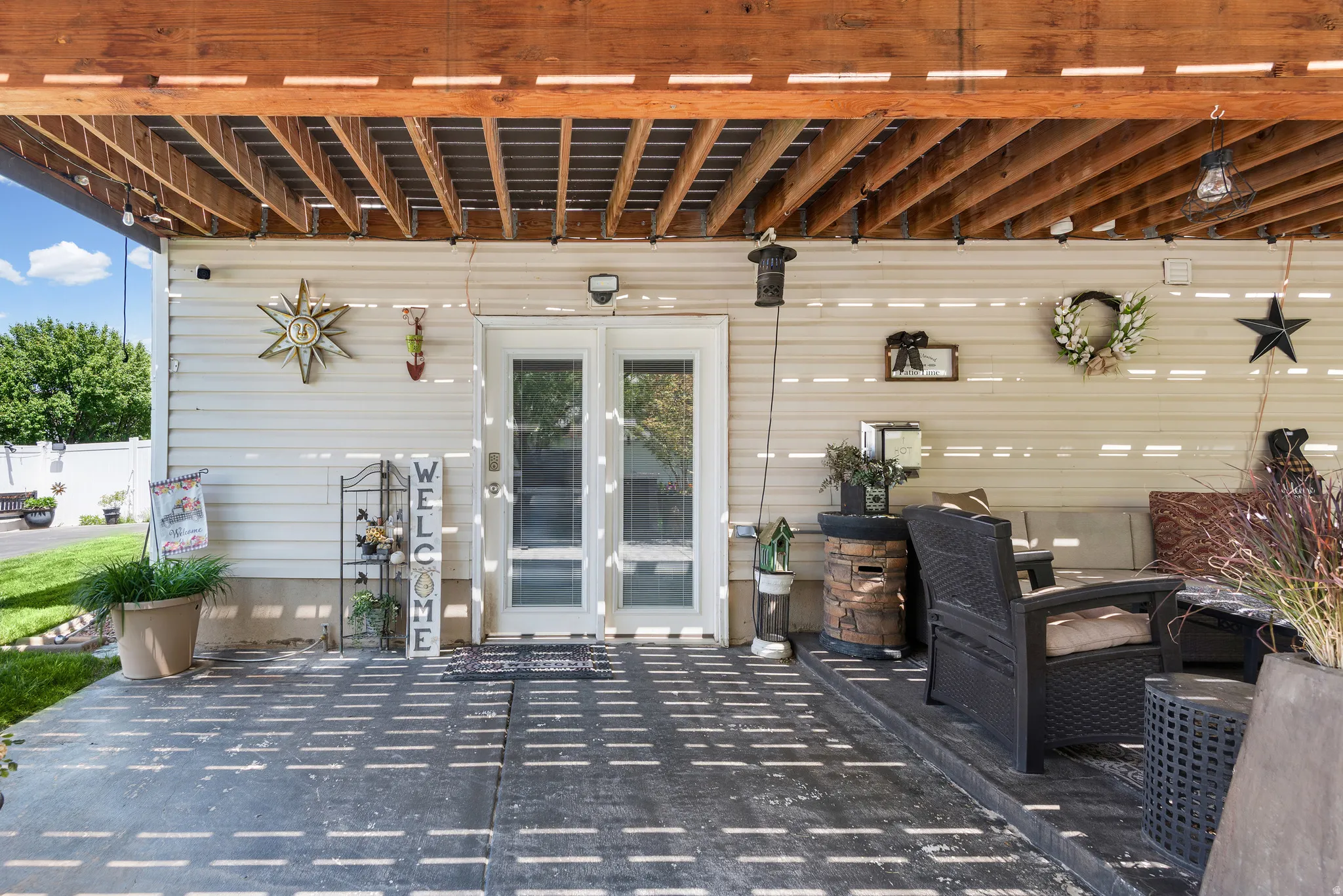 Covered patio area featuring a slatted wood ceiling, light-colored siding, and direct access through glass-paned double doors