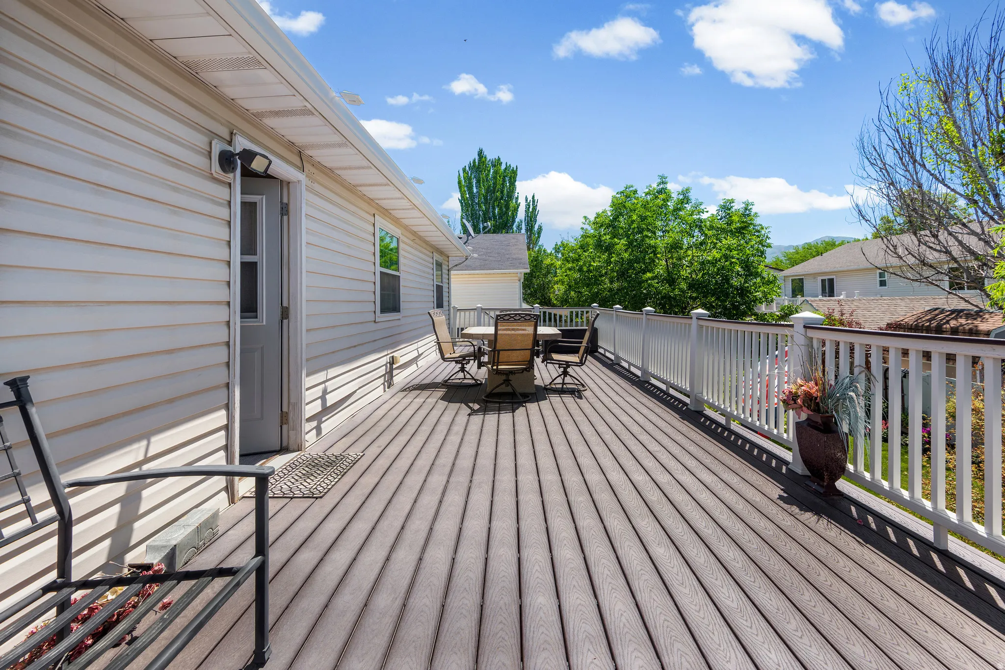 Expansive outdoor deck featuring wood-finish flooring, white railing, and a direct entry door to the home