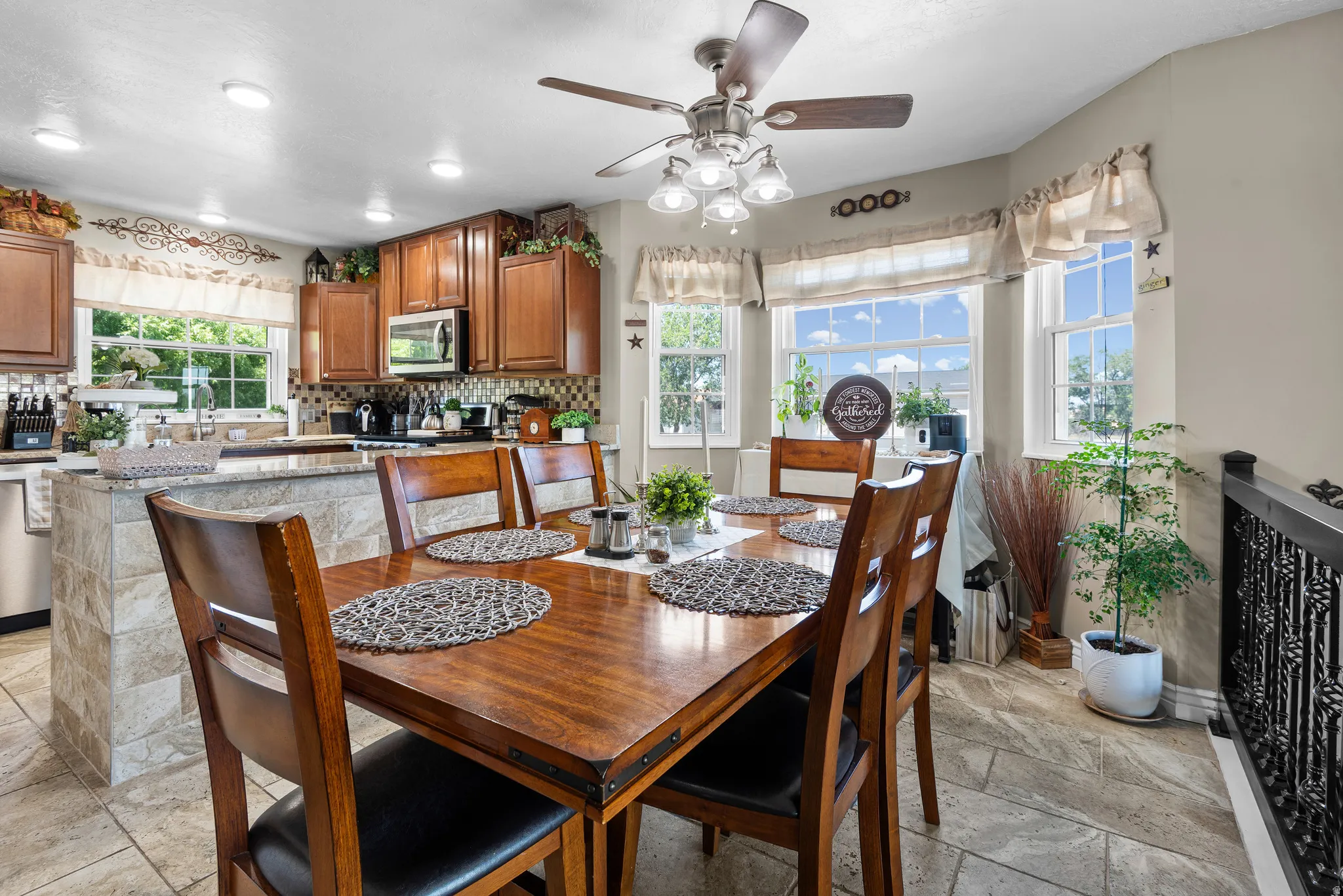 Dining area featuring a ceiling fan with integrated lighting, multiple windows, and tile flooring
