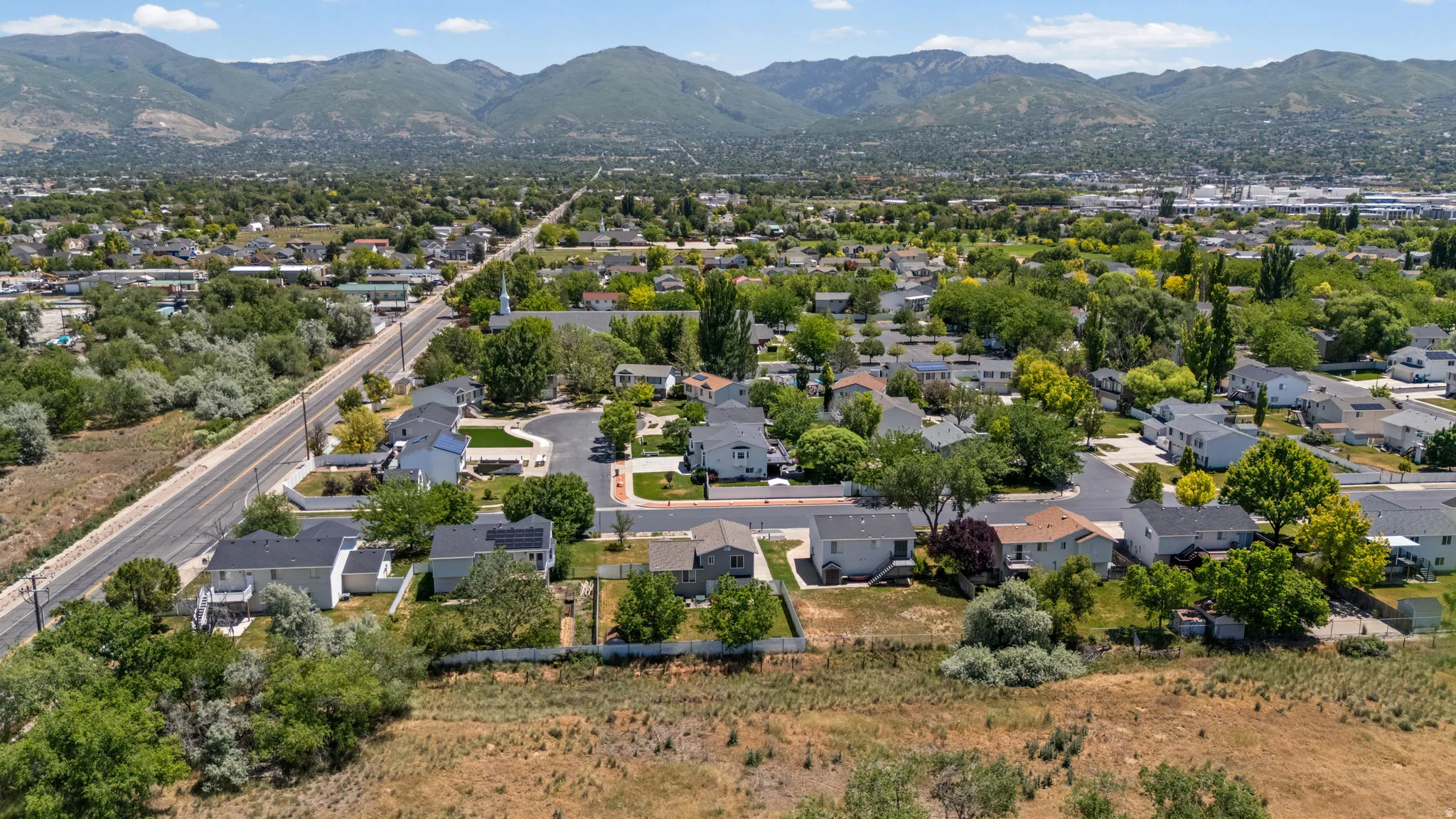 Residential area featuring a variety of homes, mature trees, and mountainous terrain in the background