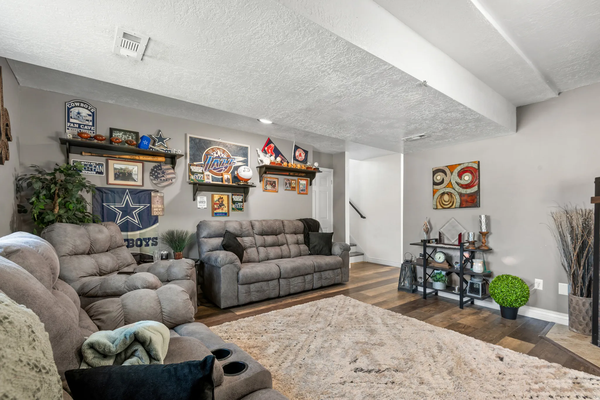 Spacious living area featuring wood-finish flooring, light gray wall paint, and a textured white ceiling