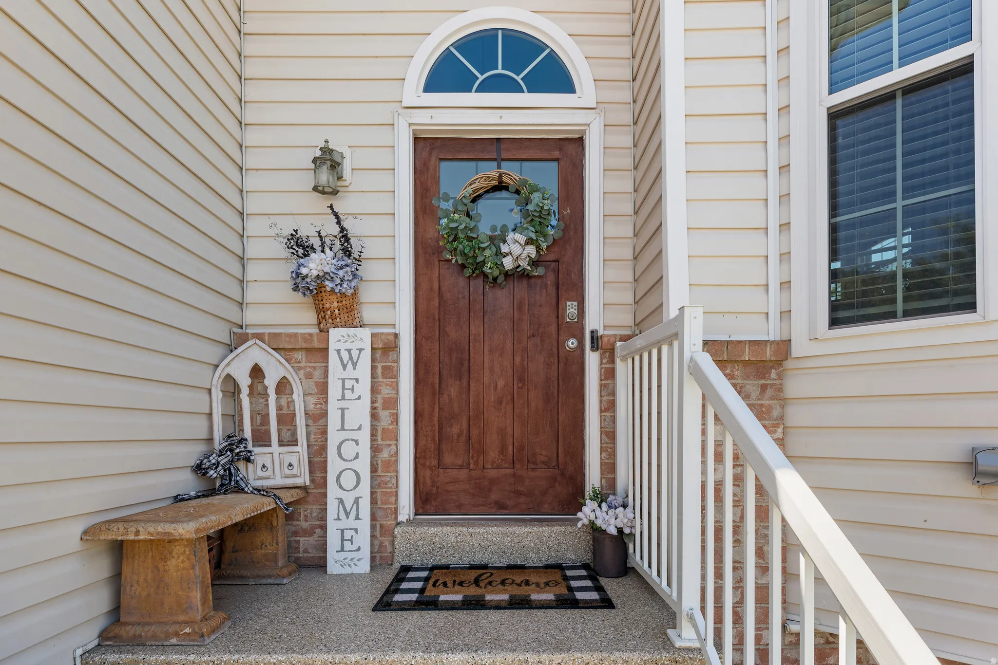 Front entry featuring a paneled wood door with an arched transom window, a brick facade accent, and light-colored siding