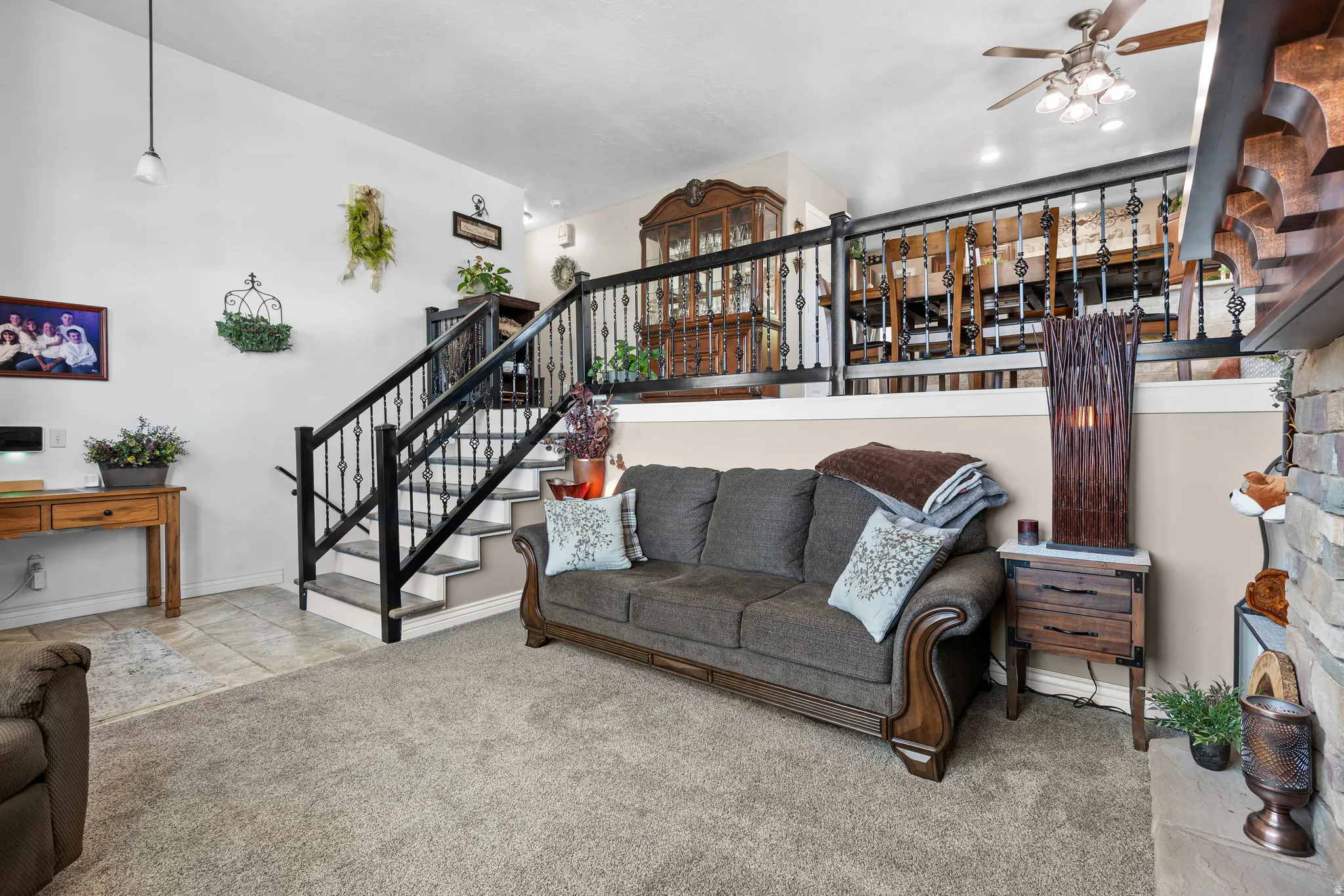 Split-level interior featuring a stone-clad fireplace and a staircase with wrought iron balusters