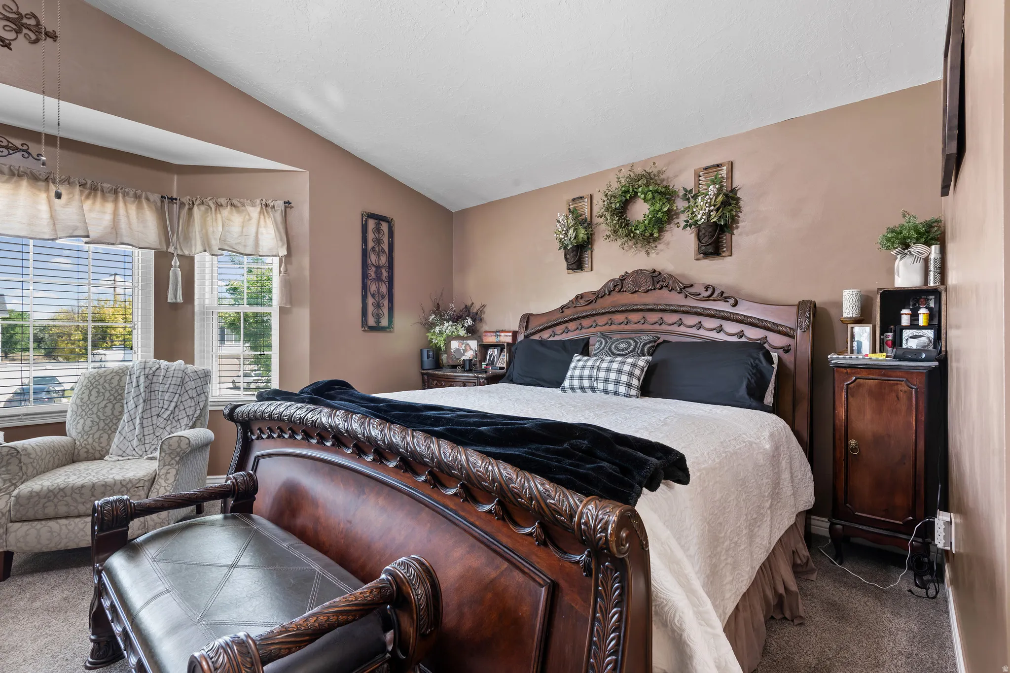 Carpeted room featuring a bay window with blinds, vaulted ceiling, and neutral wall tones
