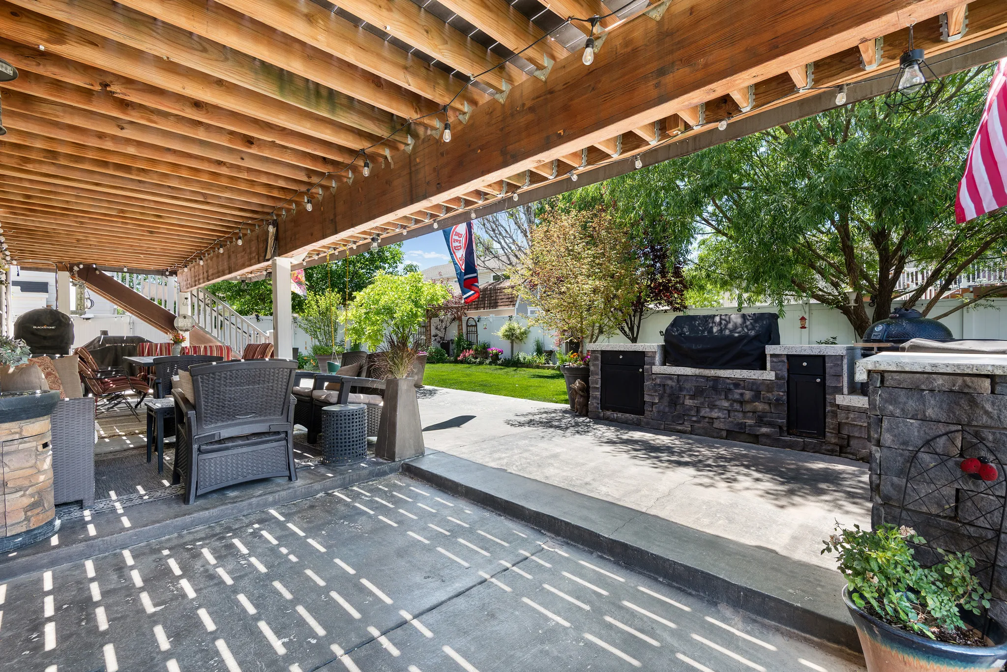 Covered patio with a wood ceiling, integrated string lighting, and direct access to an outdoor kitchen area