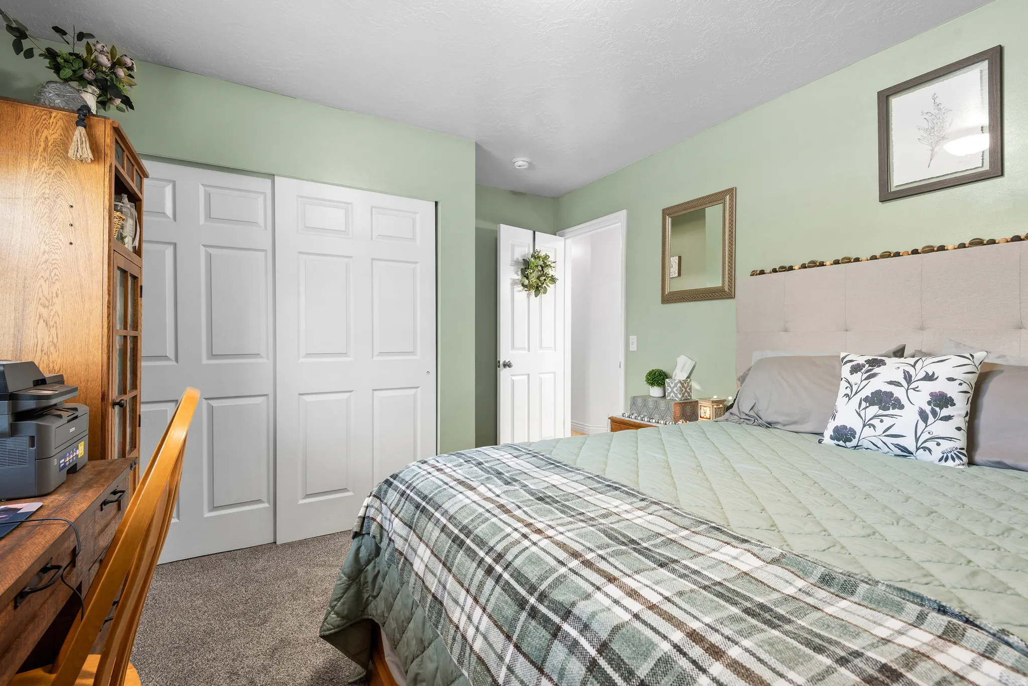 Carpeted room featuring a tufted fabric headboard, light green walls, a white paneled closet, and a white paneled door