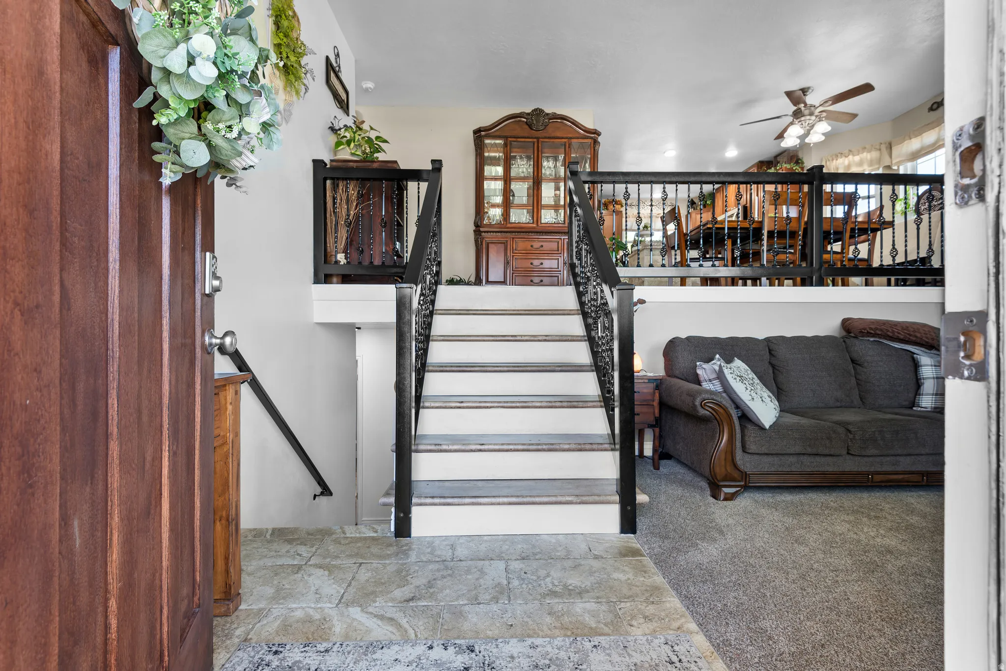 Entryway featuring stone-finish flooring, a rich wood-panel door, and a staircase with decorative iron railings