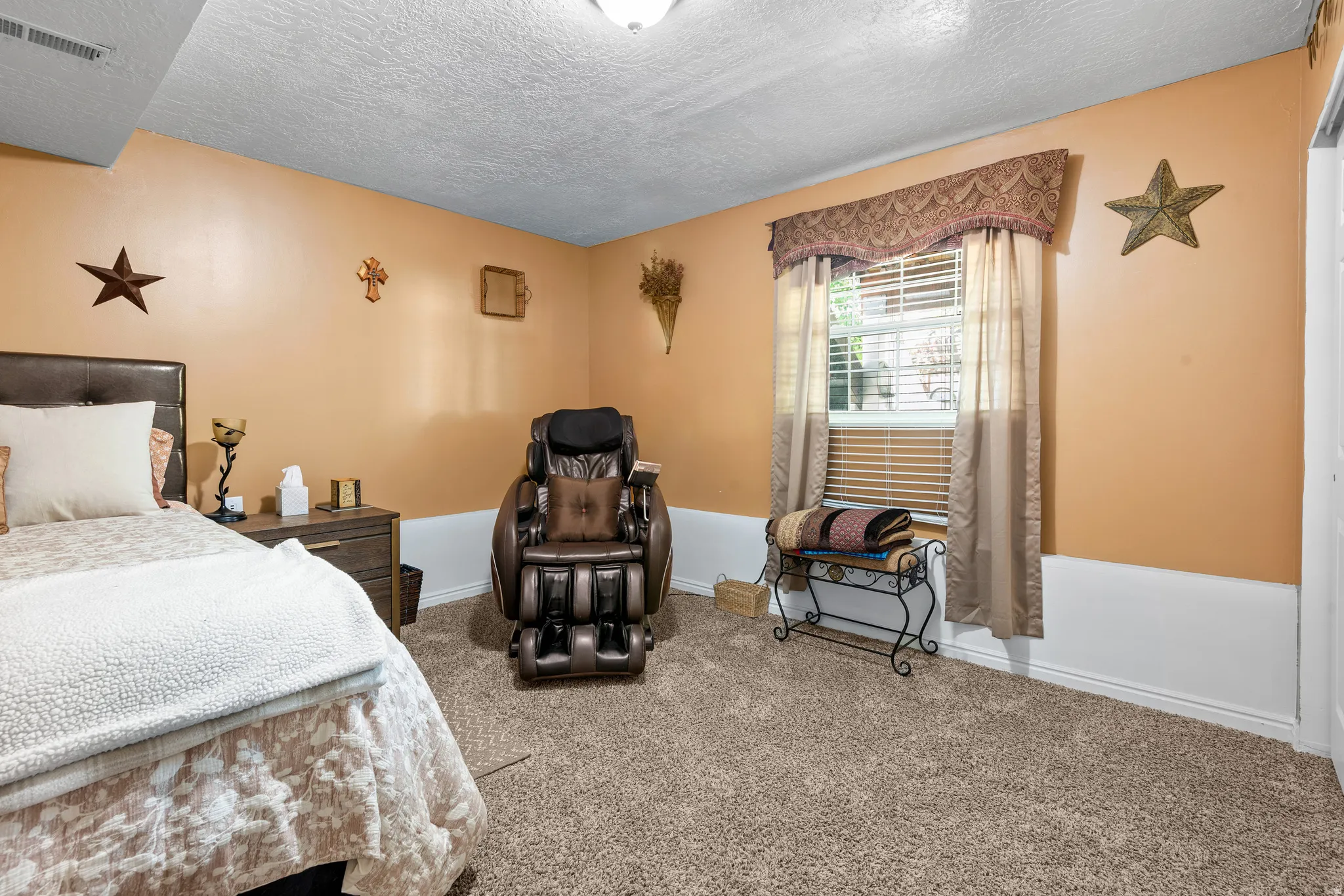 Carpeted room with a window featuring blinds and drapes, light orange walls, and white baseboards