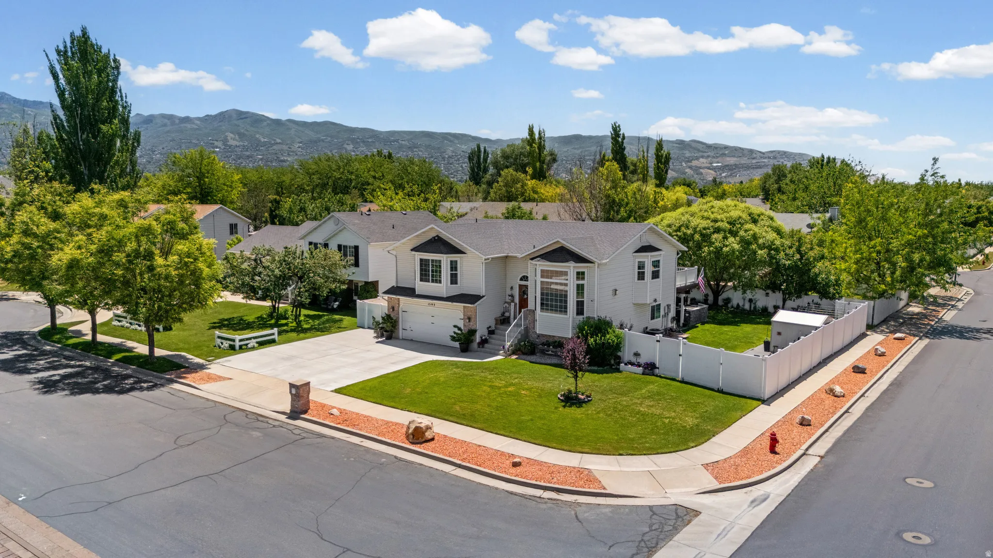 Contemporary two-story residence with a light-toned exterior and dark roof, situated on a corner lot