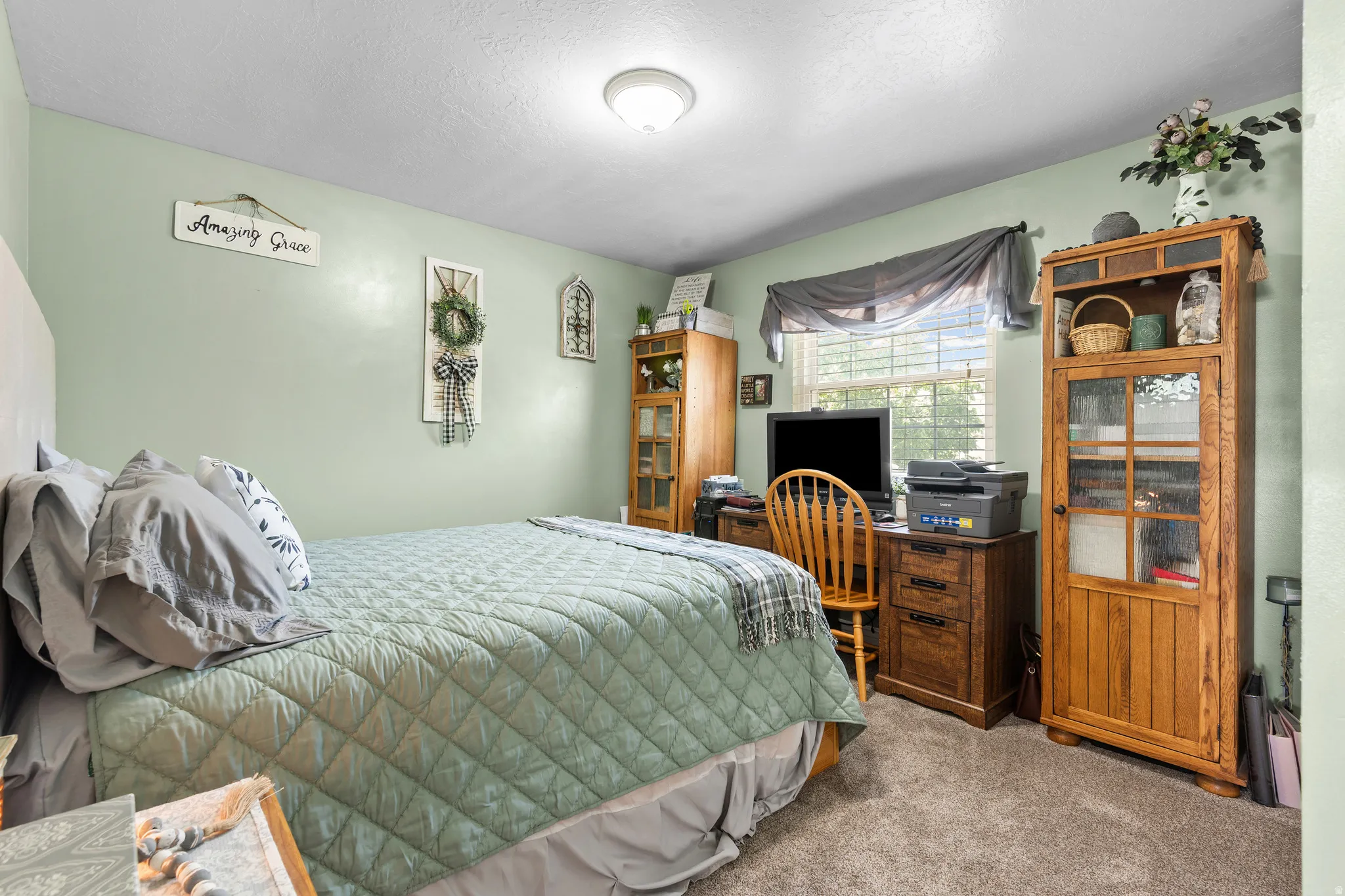 Carpeted bedroom featuring light green walls and a single window with blinds