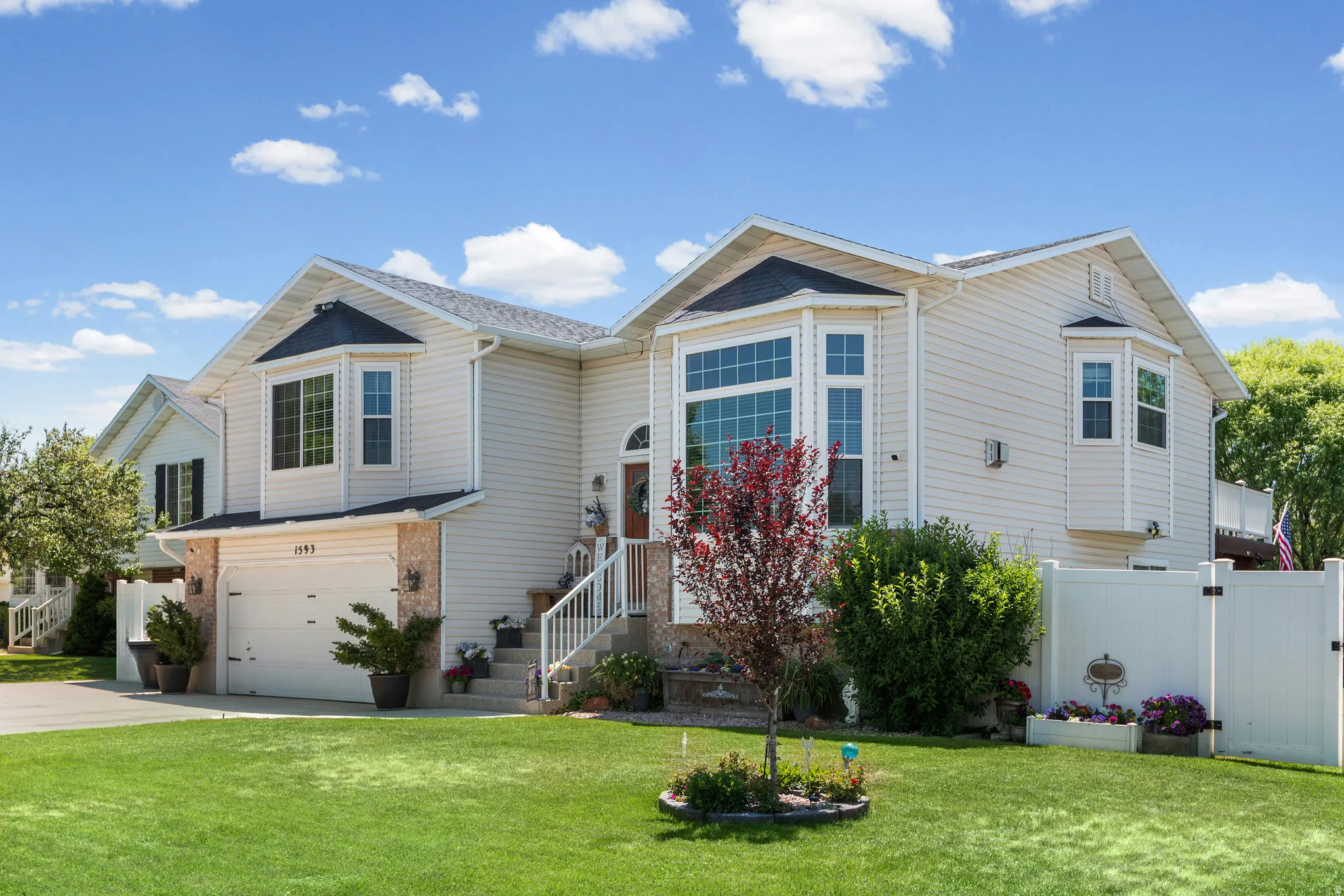 Split-level residence featuring light-colored siding, a prominent bay window, and an attached garage with a paved driveway
