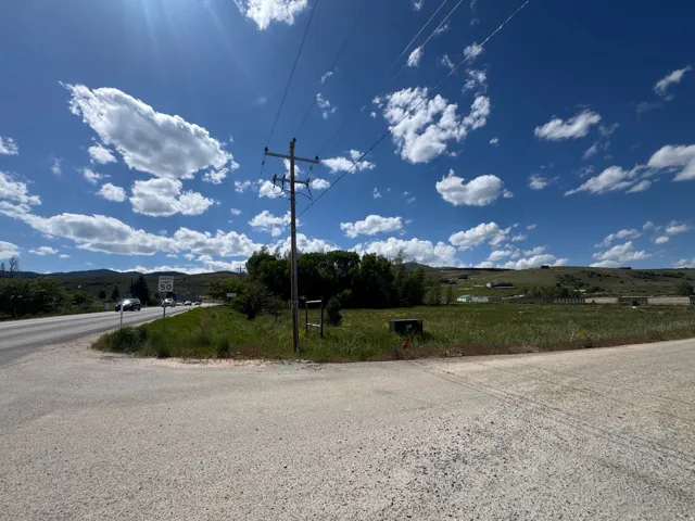 Expansive undeveloped land with a partial paved road frontage and distant hillside backdrop