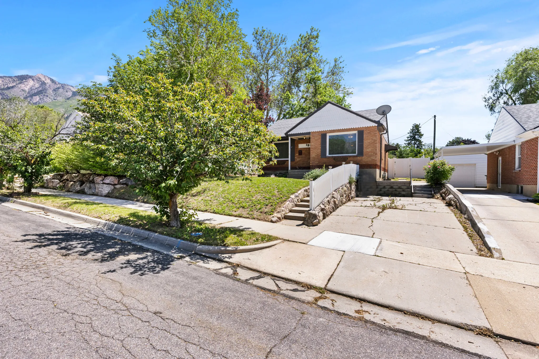Brick exterior residence featuring a front lawn with mature trees and a concrete driveway