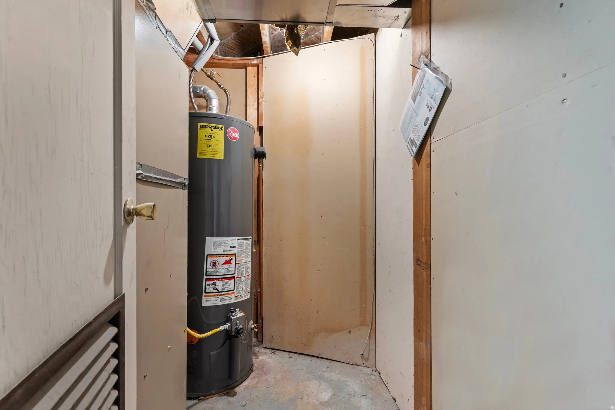 Utility area featuring a water heater unit, exposed ceiling joists, and unfinished wall surfaces