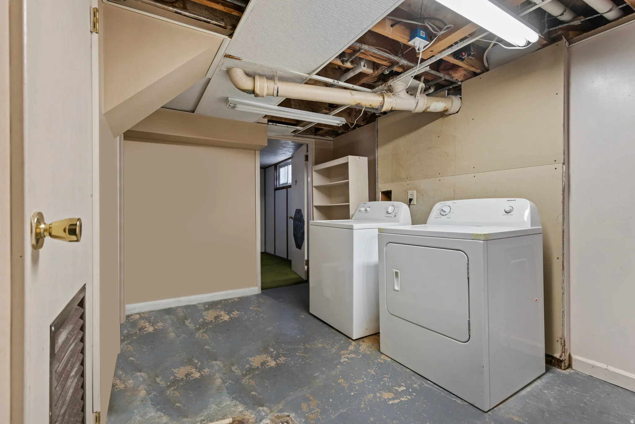 Utility area featuring a washer and dryer, exposed ceiling joists, overhead fluorescent lighting, and a partial dropped ceiling
