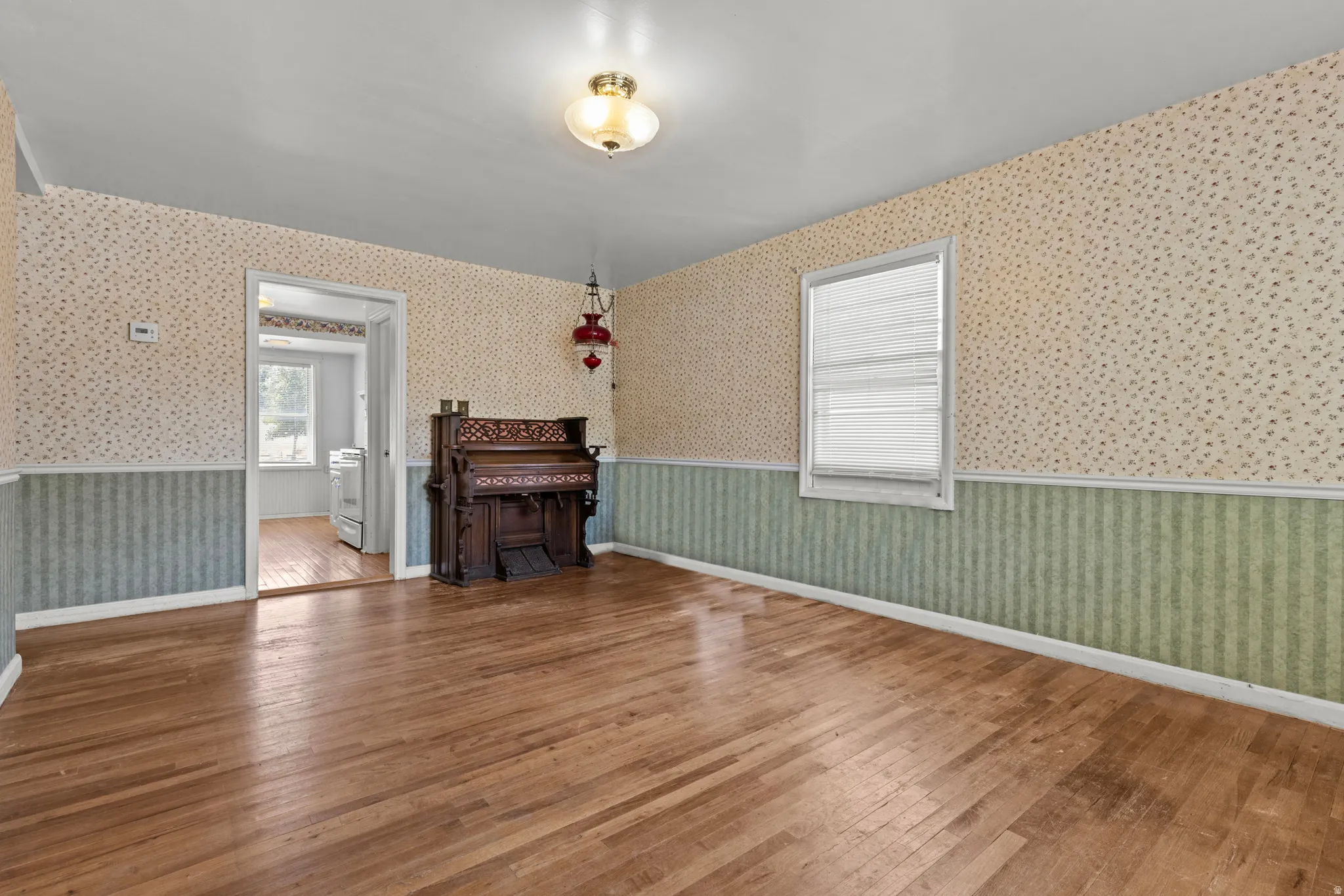 Hardwood flooring complements the patterned wallpaper and chair rail detailing