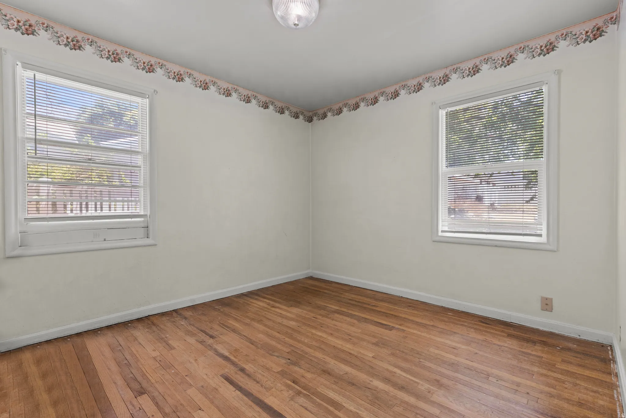 Hardwood flooring throughout, complemented by two windows with horizontal blinds