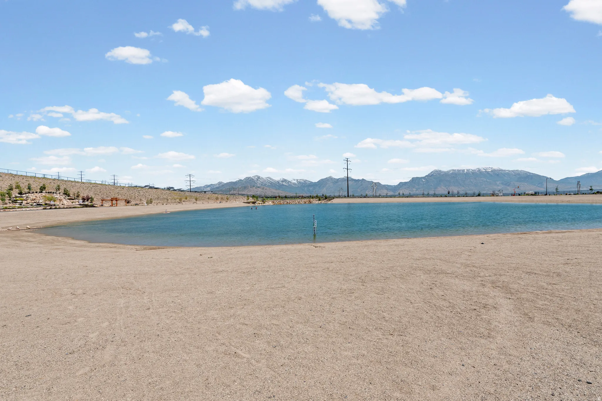 Expansive sandy beach area bordering a tranquil lake, with a backdrop of distant mountains