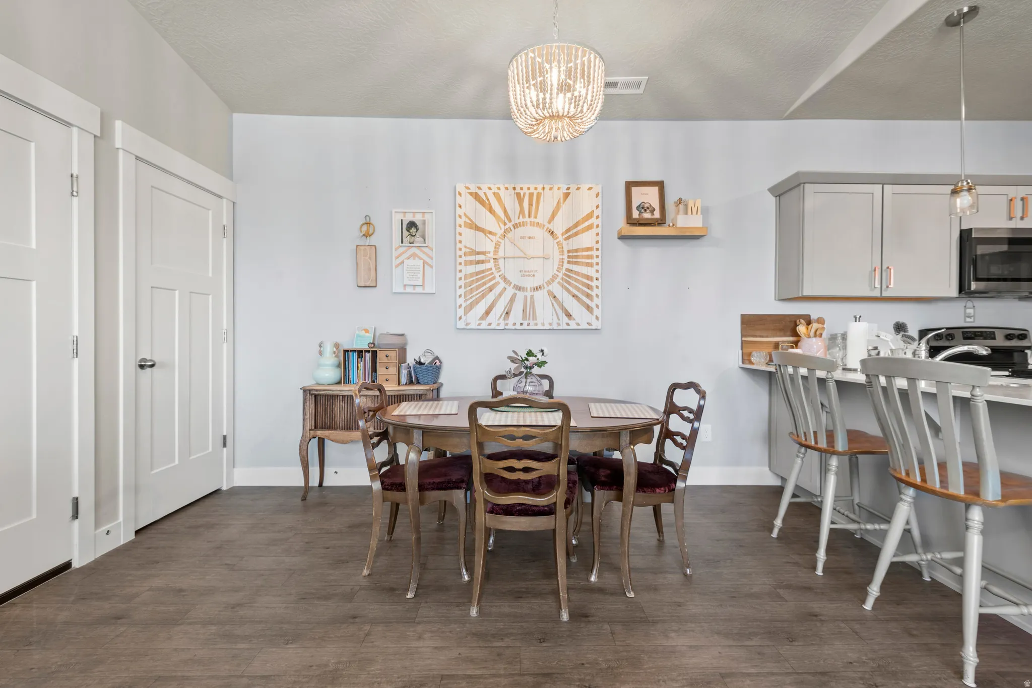 Dining area featuring wood-finish flooring, a contemporary chandelier, and two paneled doors with modern hardware