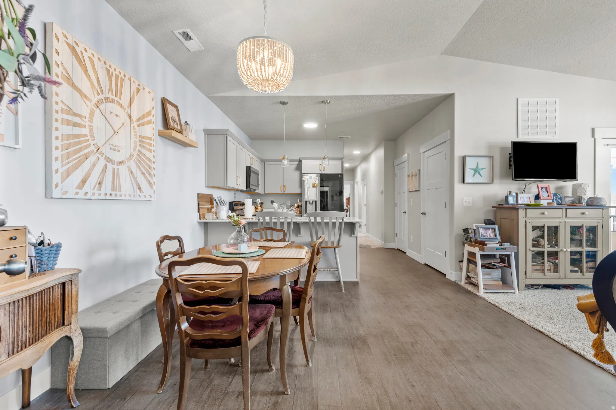 Open-concept living space featuring wood-finish flooring, vaulted ceilings, and a beaded chandelier
