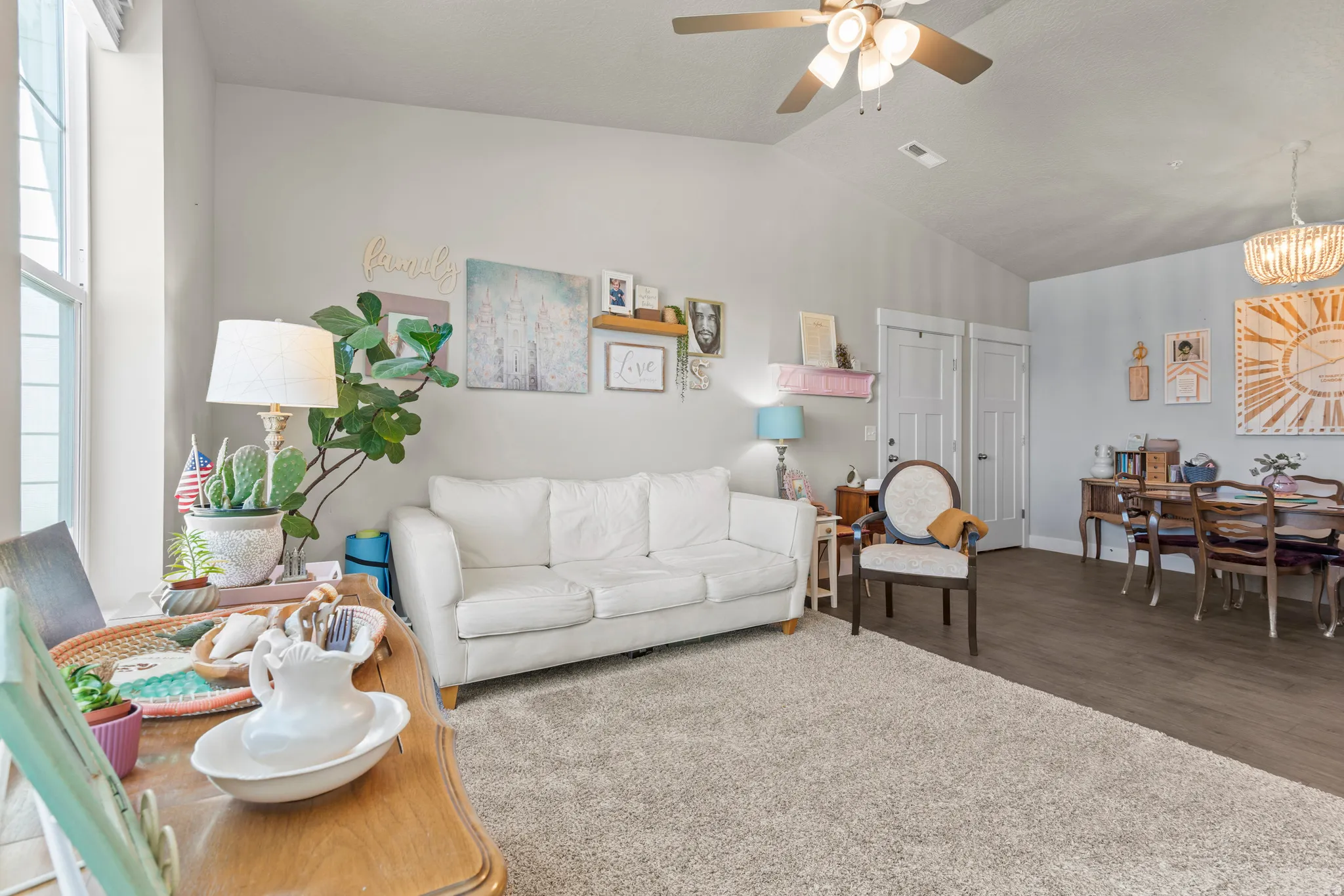 Living area featuring a light gray wall color, a ceiling fan with light fixture, and wood-finish flooring in the dining area