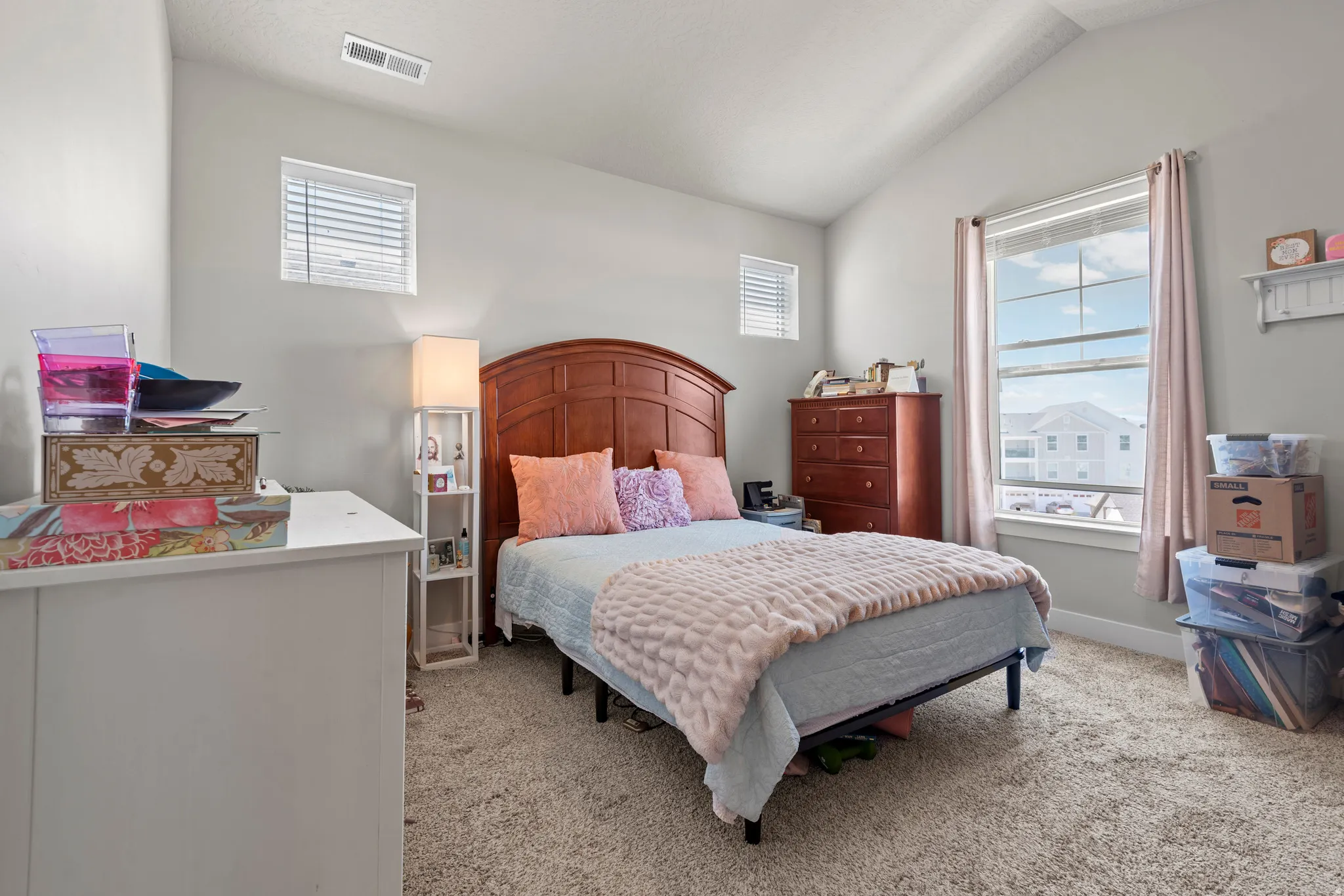 Bedroom featuring a vaulted ceiling, light gray walls, and plush carpet flooring