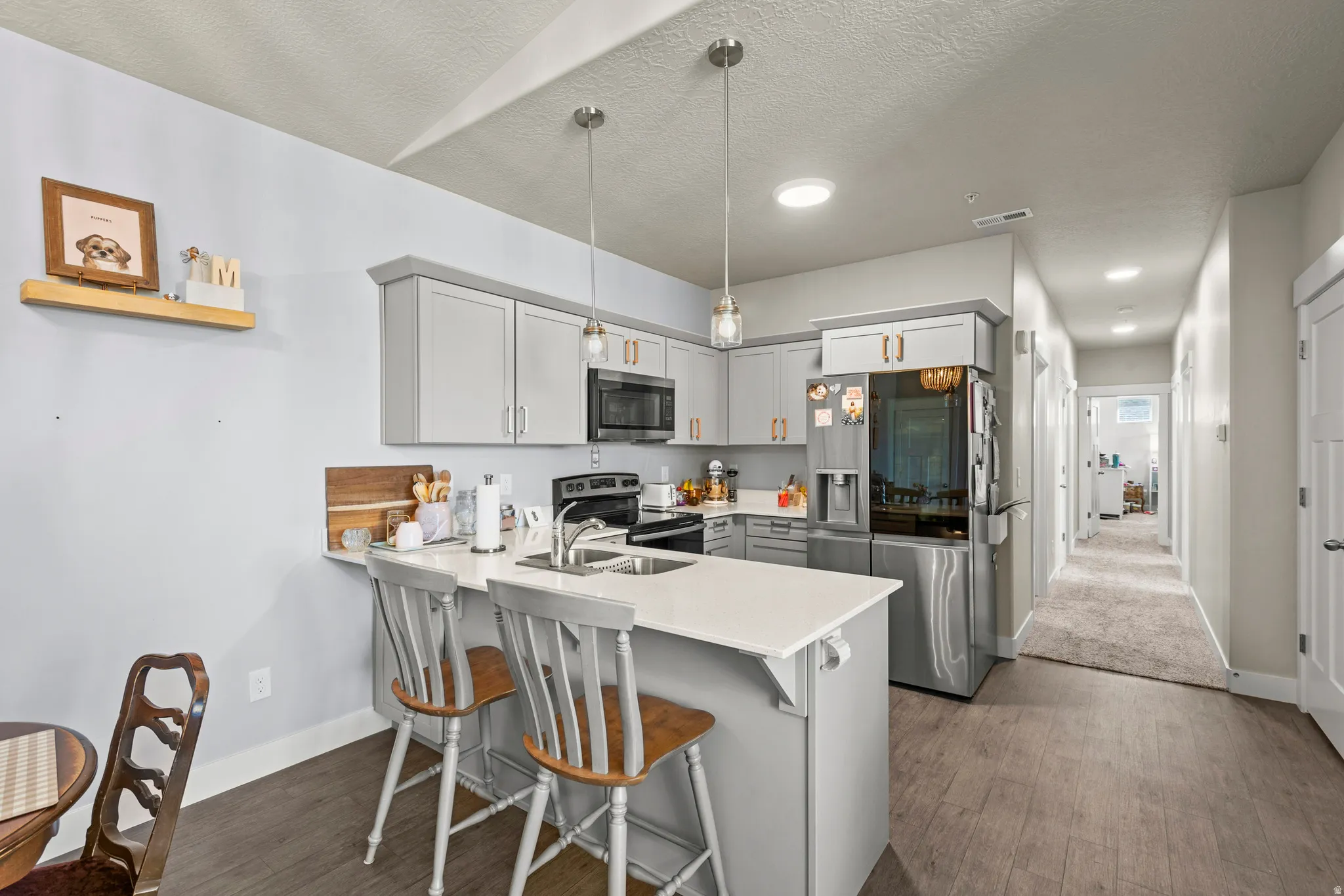 Modern kitchen featuring light gray cabinetry, stainless steel appliances, and a central island with a white countertop and seating