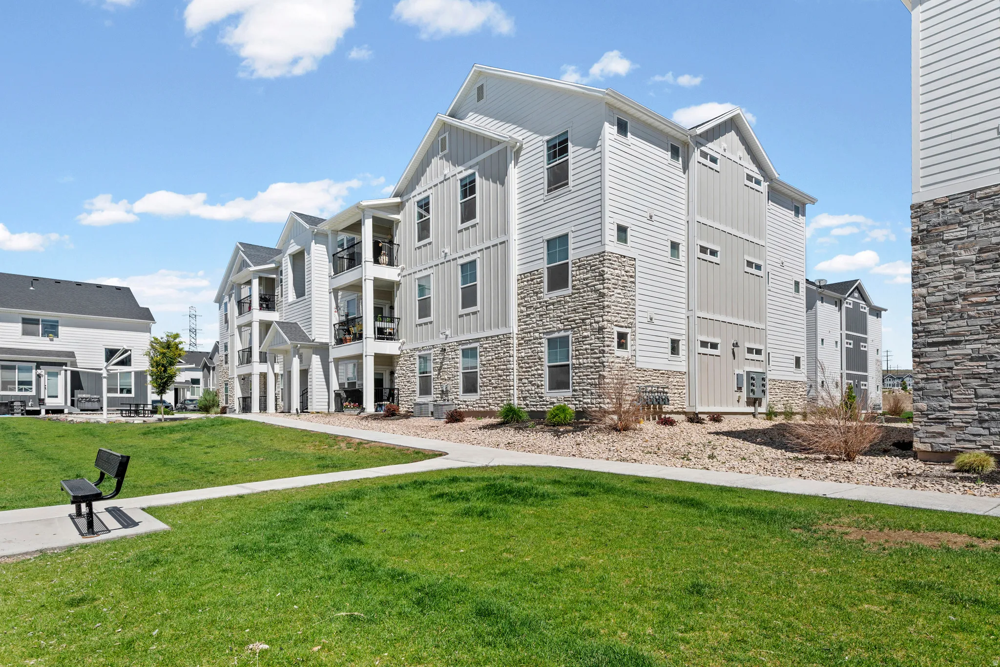 Multi-story residential buildings featuring light-toned siding and stacked stone veneer accents