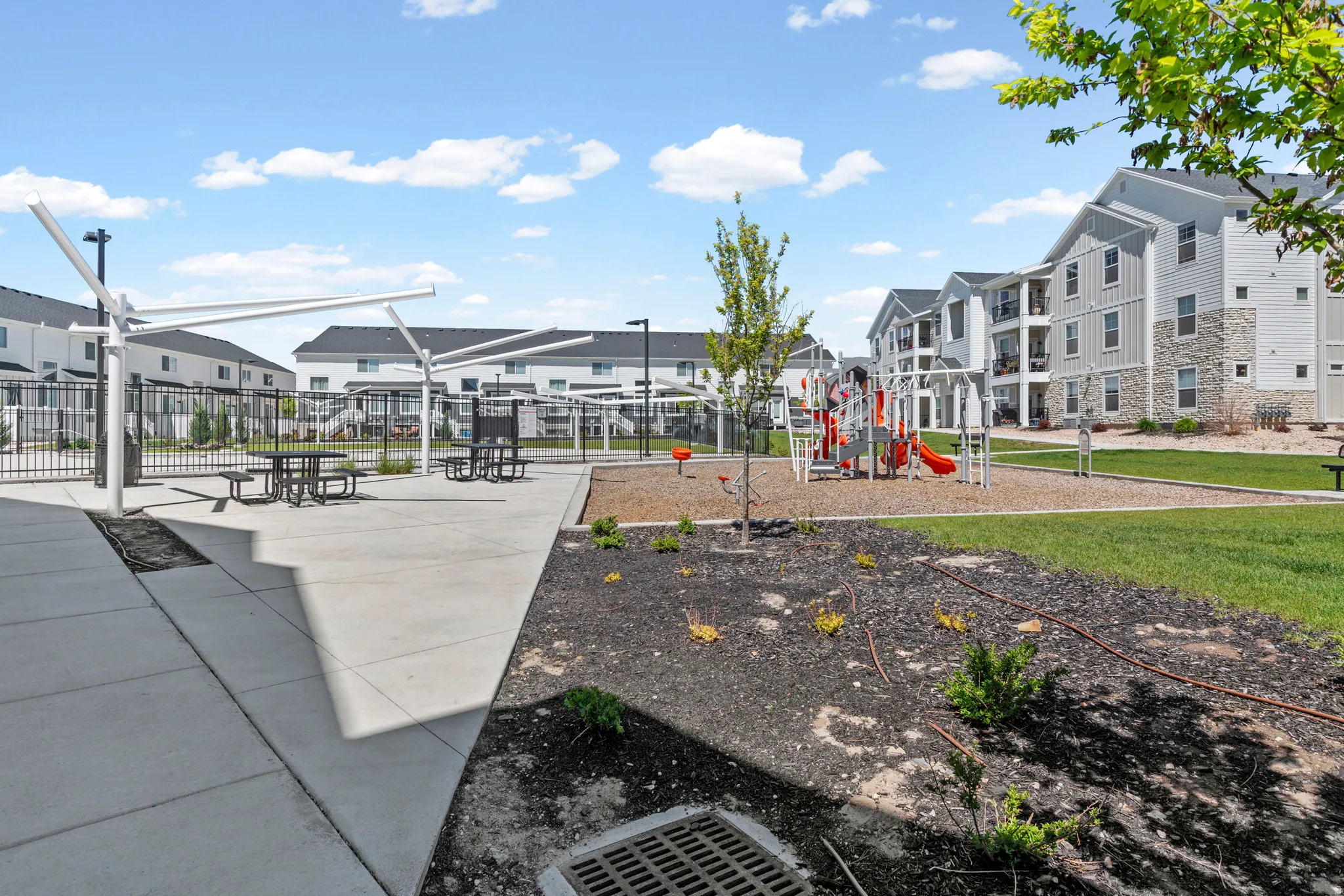 Community amenities featuring a playground with a wood chip surface, green spaces, and a paved patio area