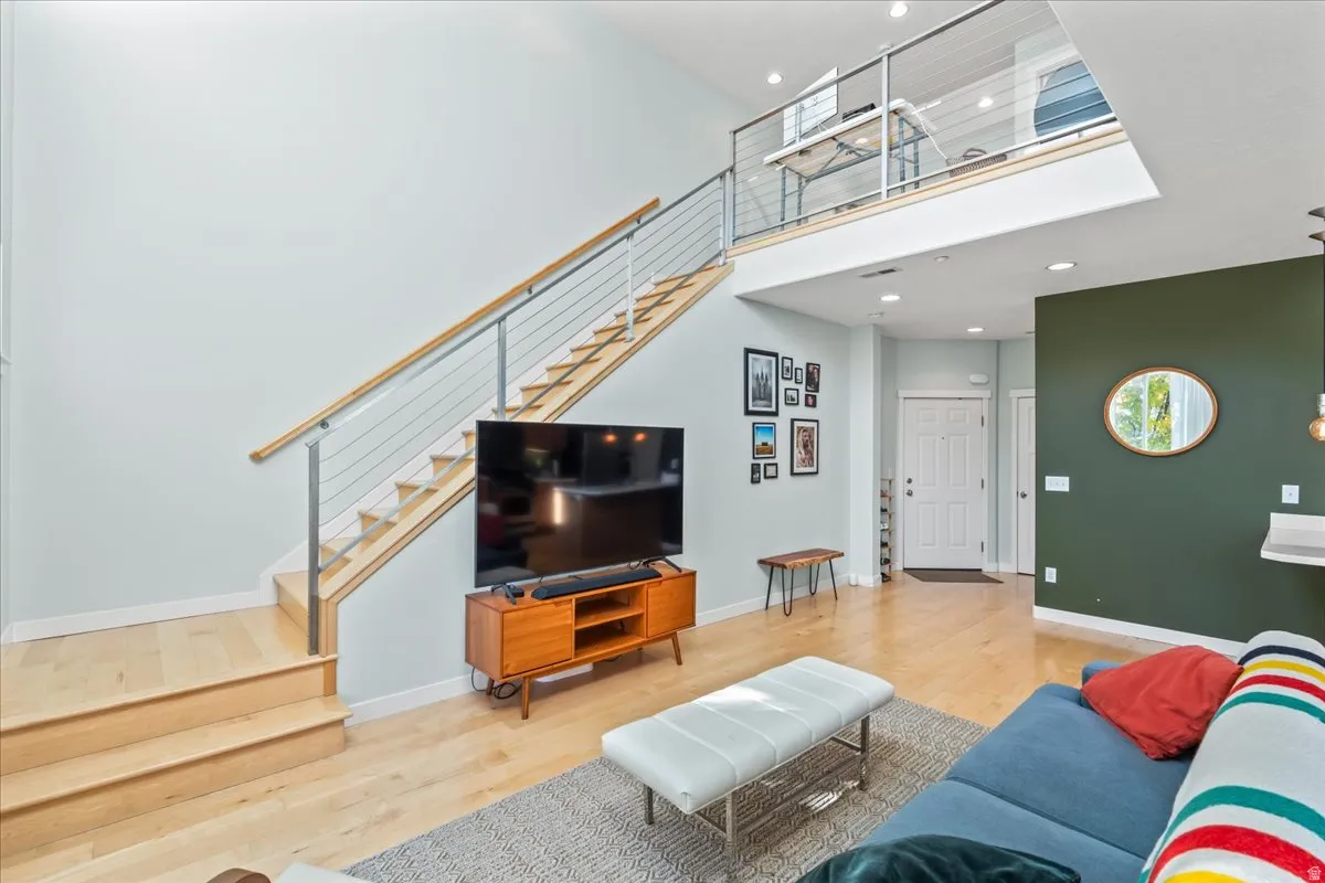 Two-story living area featuring a light wood flooring and a modern cable railing staircase