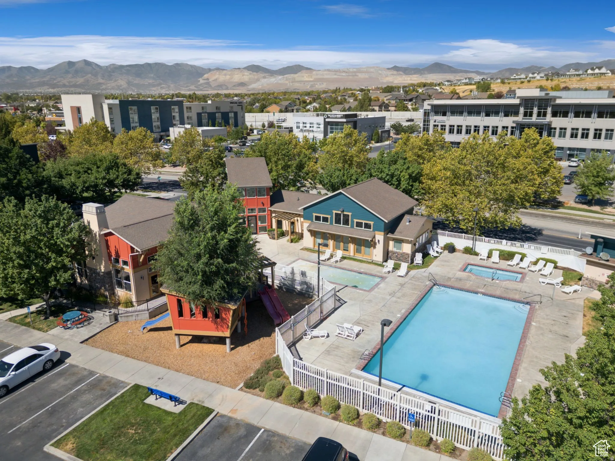 Community amenity area featuring a large swimming pool, two hot tubs, and a dedicated play structure
