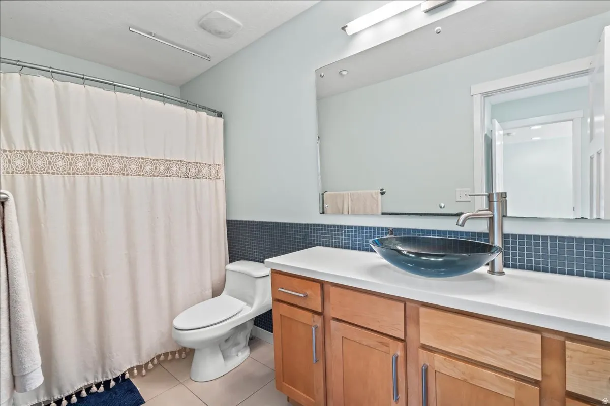 Bathroom vanity featuring a vessel sink with a brushed nickel faucet, a white countertop, and wood-finish cabinetry